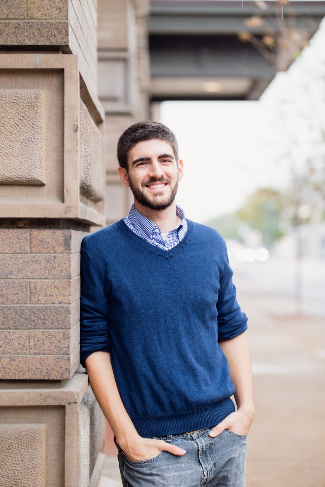 travis leaning on brick building