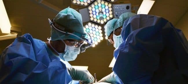 two surgeons working on a patient under the lights