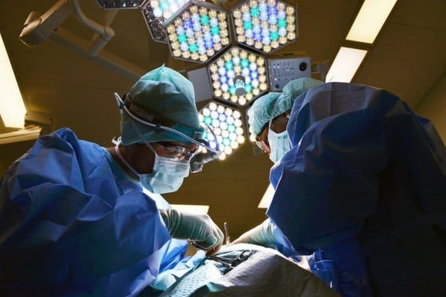 two surgeons working on a patient under the lights