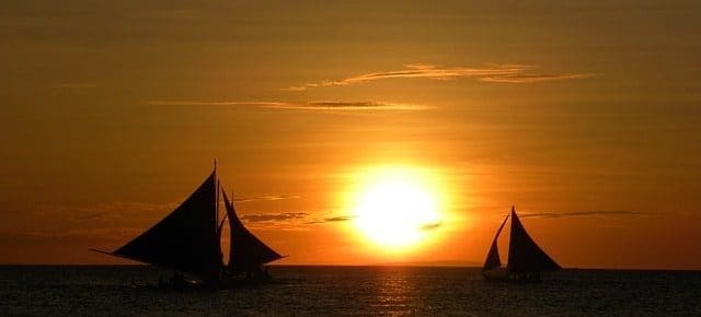sunset on water with two sailboats