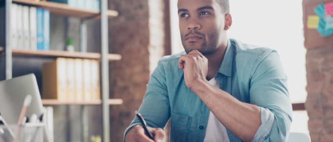 black male looking pensive while writing in book