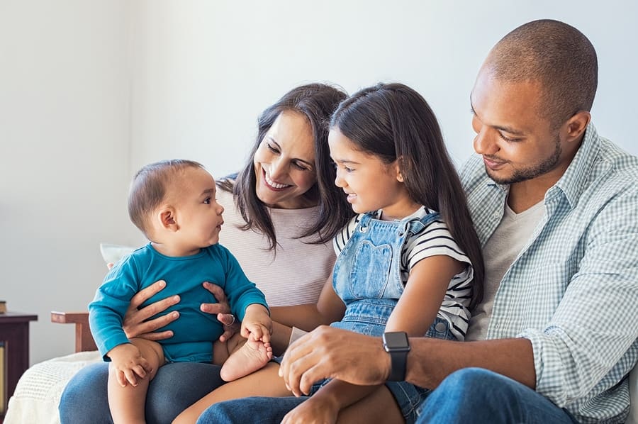 mom, dad, baby and young daughter on couch