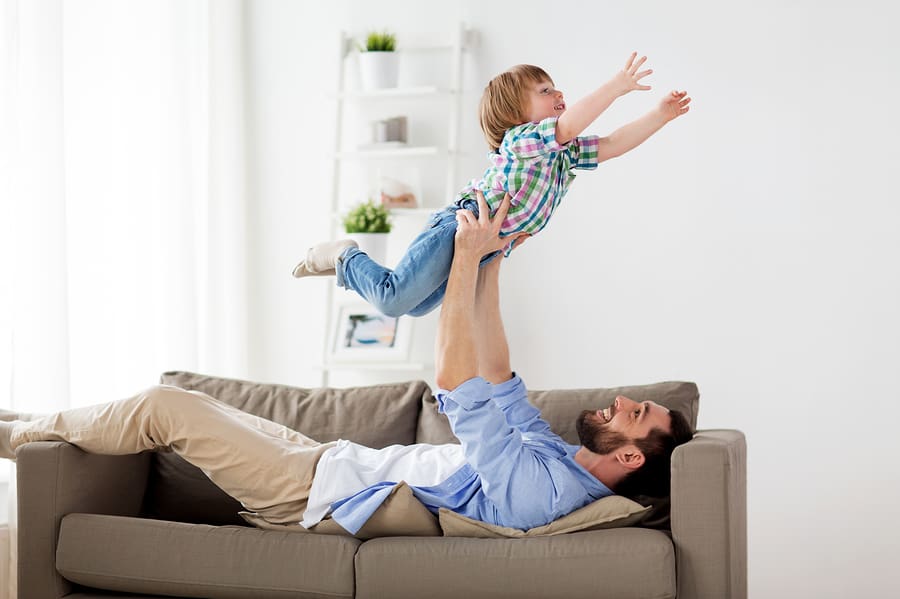 dad on couch holding son in airplane pose