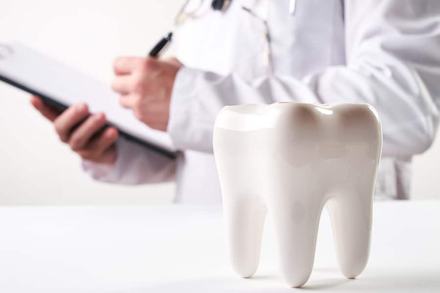 large ceramic tooth with person in background writing on clipboard