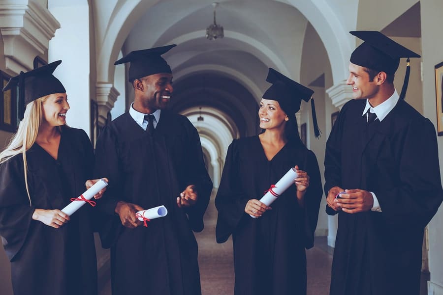 four students in gap and gown holding scrolls