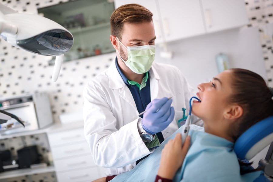 Male dentist repairing girls tooth on clinic