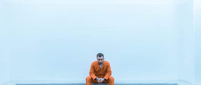 Prisoner Sitting On Bench In Prison Room