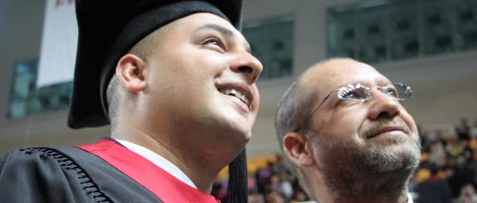 male in gap and gown with father looking up