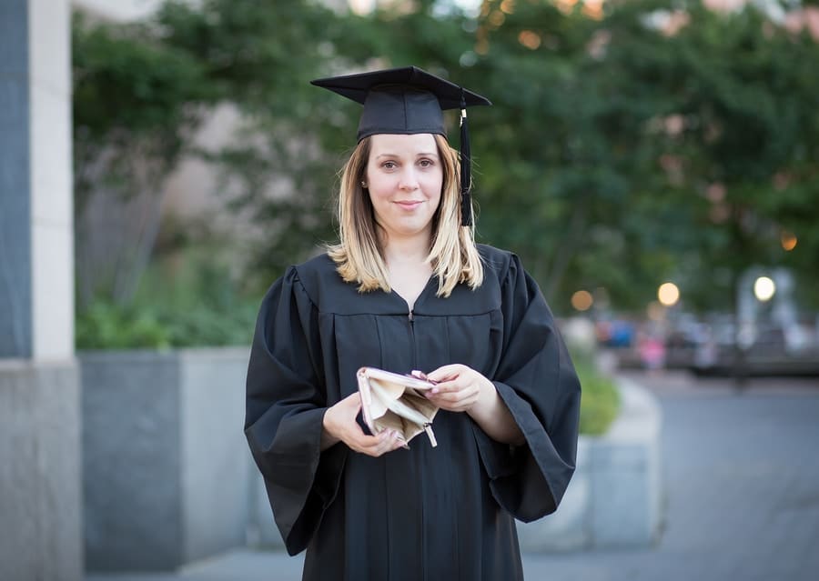 Portrait of female college student in graduation day broke and in debt