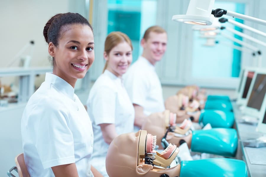 happy dental students working on mannequin teeth