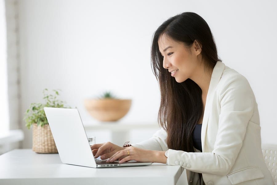 female at desk in white room on laptop