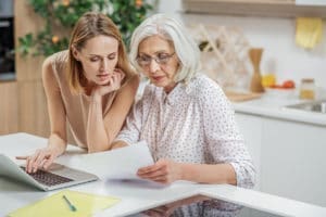 older women with female in kitchen looking at paperwork