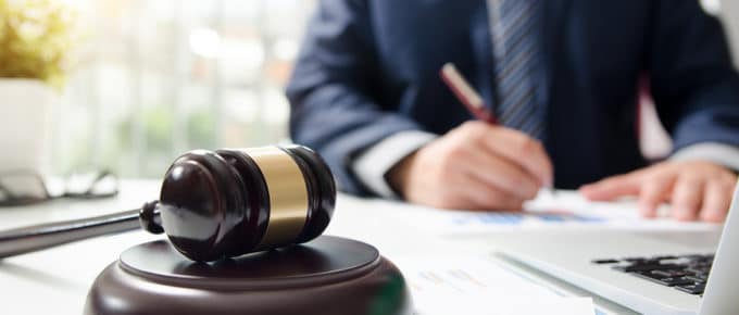 faceless male in suit writing with gavel on desk