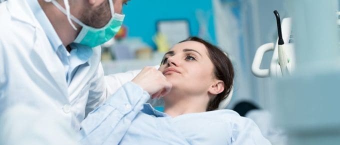 male dentist looking at female patient in chair