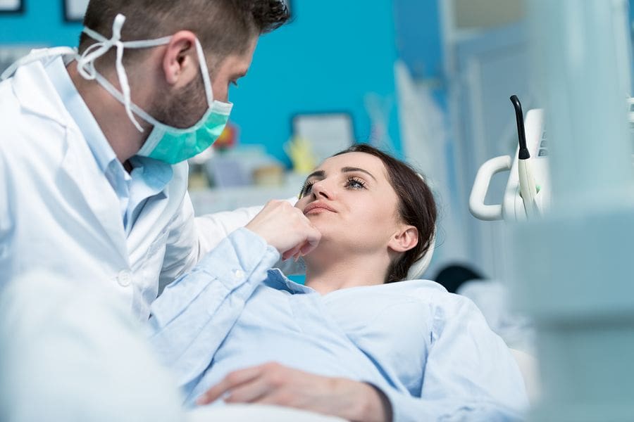 male dentist looking at female patient in chair