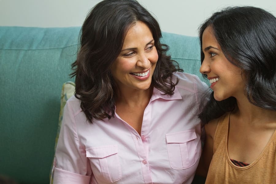 mom and daughter smiling at each other sitting on couch