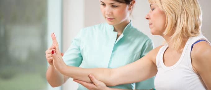 female Physical therapist working on female hand