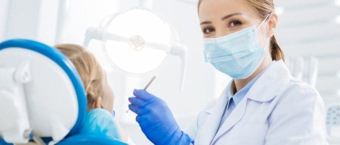dental student with mask working on patient in chair