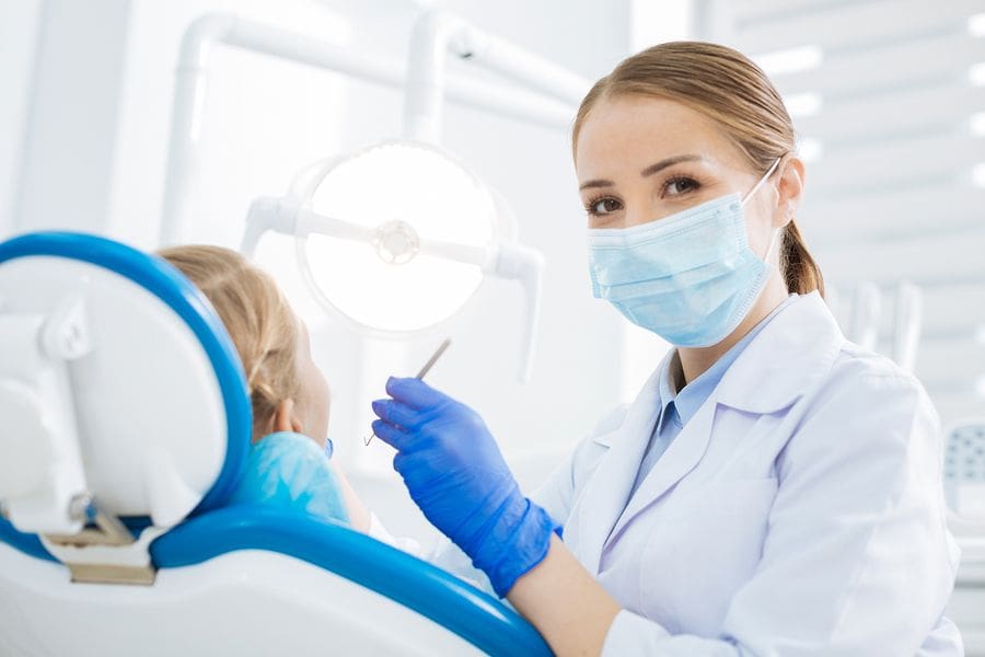 dental student with mask working on patient in chair