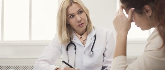 female dr writing in a notebook with a female patient