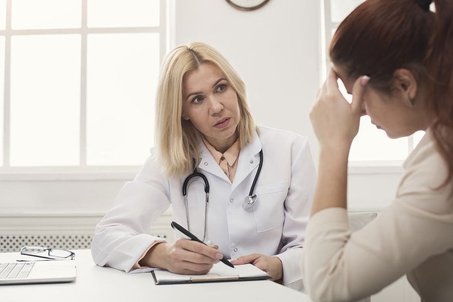 female dr writing in a notebook with a female patient