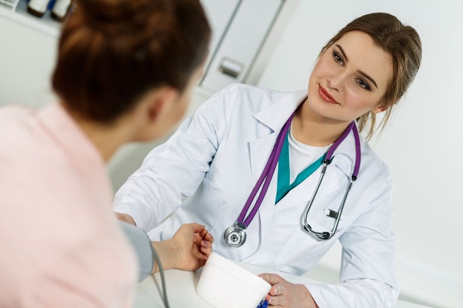 female Dr taking blood pressure of male patient