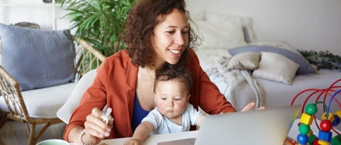 young-woman-working-laptop-baby-sitting-lap