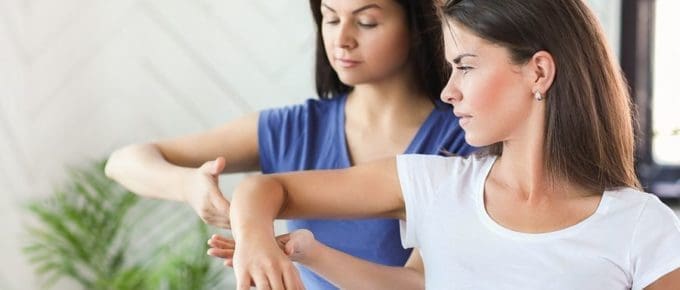 physical therapist working on female patients elbow