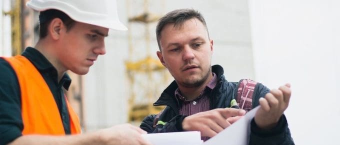 man in hard hat looking at papers with male worker