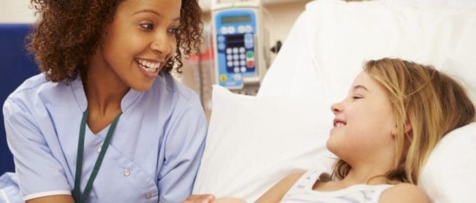 female nurse holding hands with young girl in a hospital bed