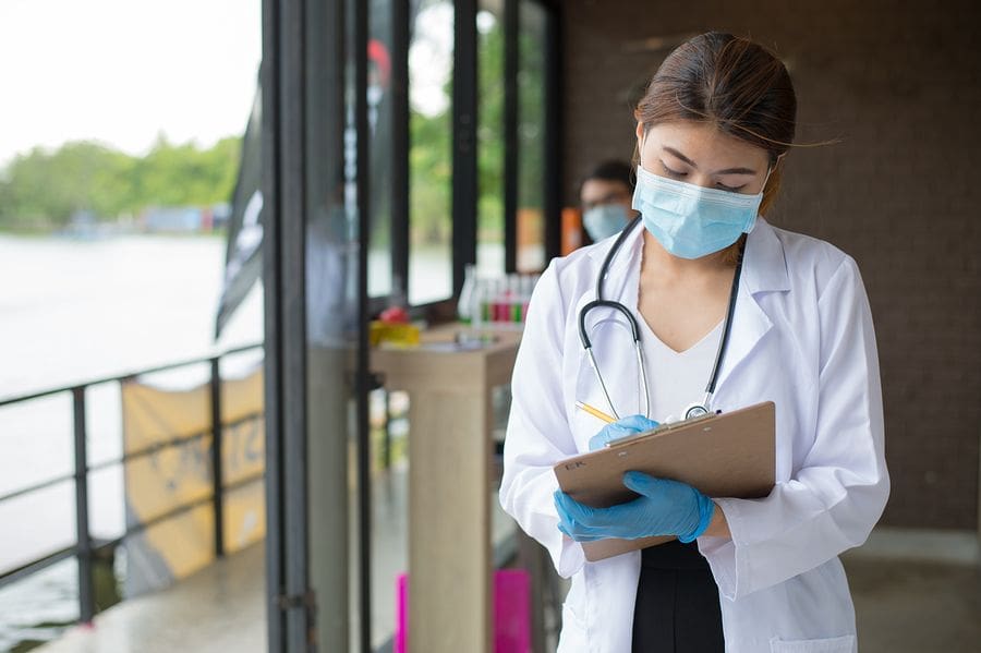 female resident working on clipboard with face mask