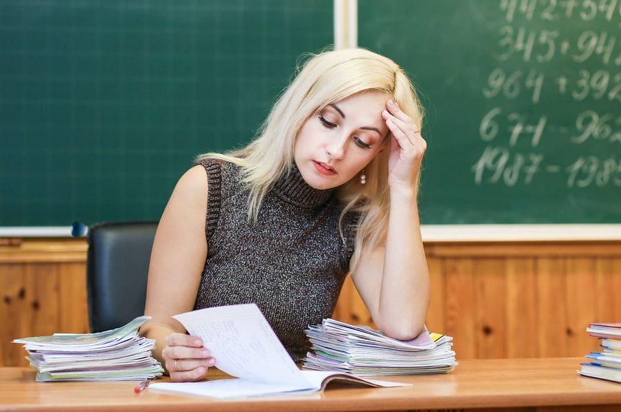 Blonde female teacher reading homework