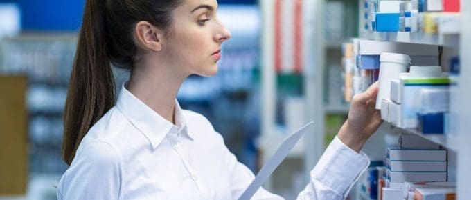 Female pharmacist stocking shelves