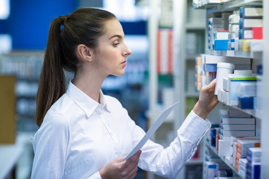 Female pharmacist stocking shelves