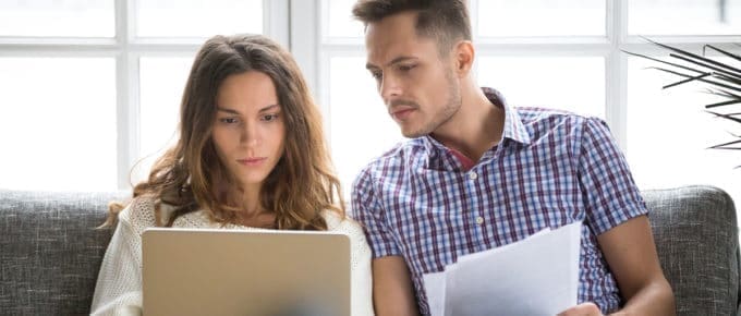 couple looking at laptop while paying bills