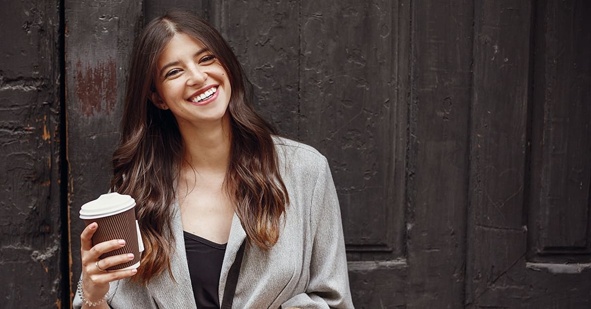 young woman smiling holding coffee