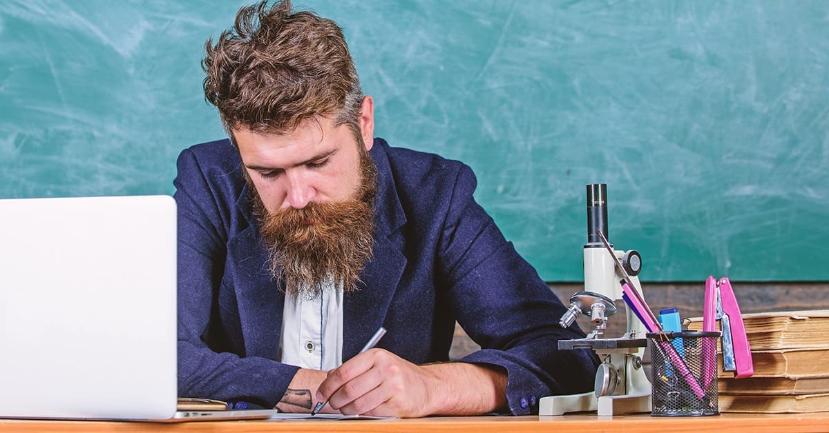 male-teacher-paperwork-desk-laptop