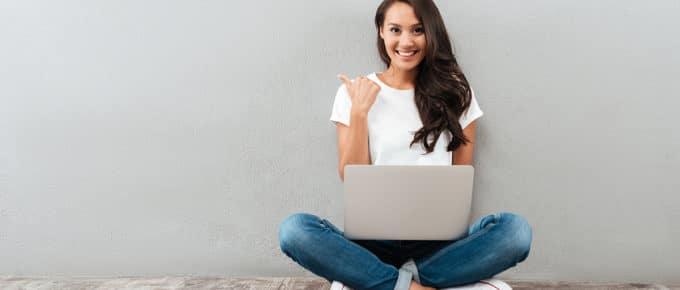 young-woman-smiling-pointing-away-laptop