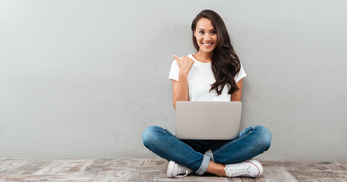 young-woman-smiling-pointing-away-laptop