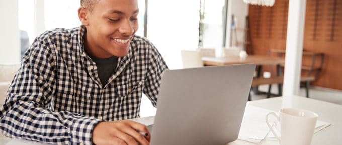 male-teenager-smiling-using-laptop