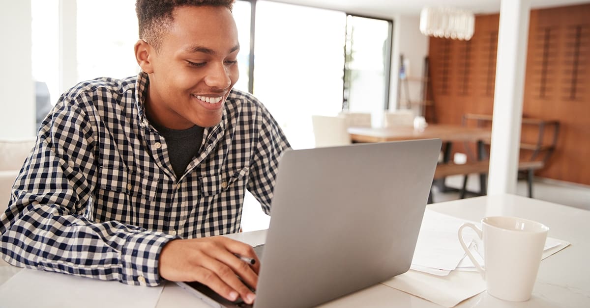 male-teenager-smiling-using-laptop