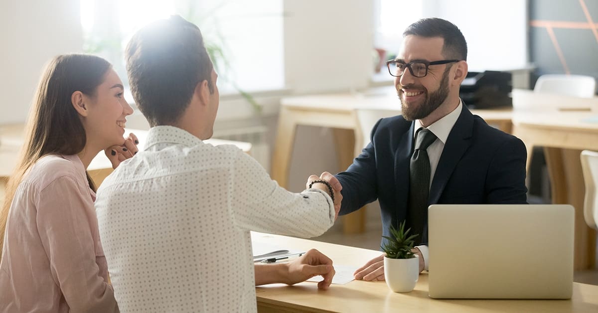 smiling-couple-shaking-hands-with-lawyer