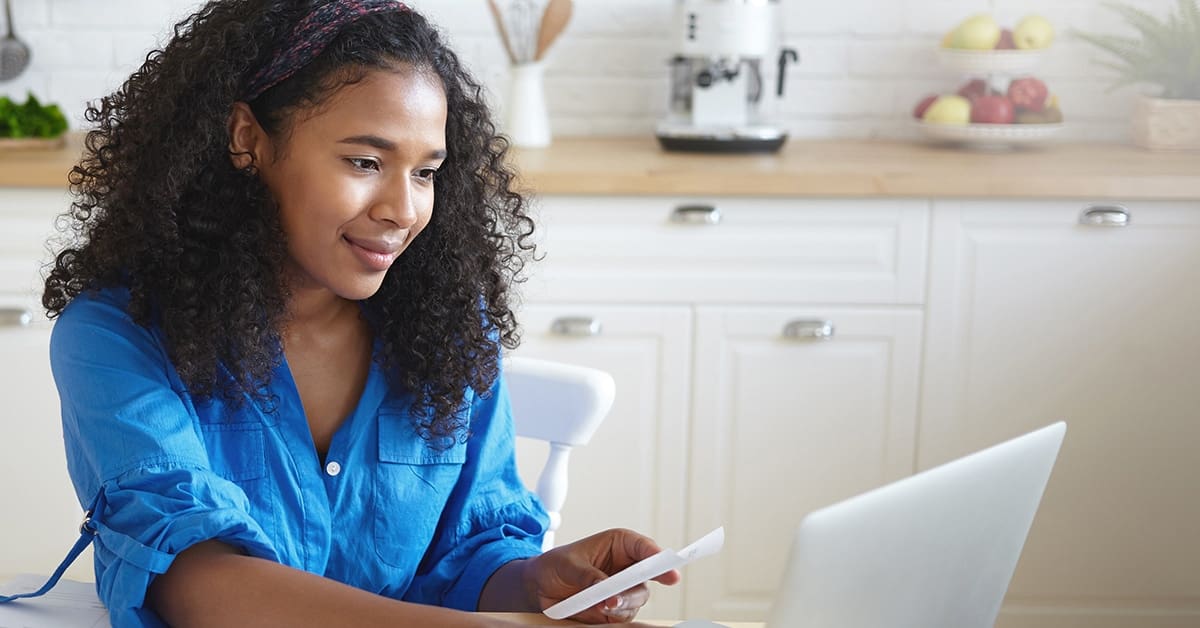 smiling-woman-paying-bills-laptop