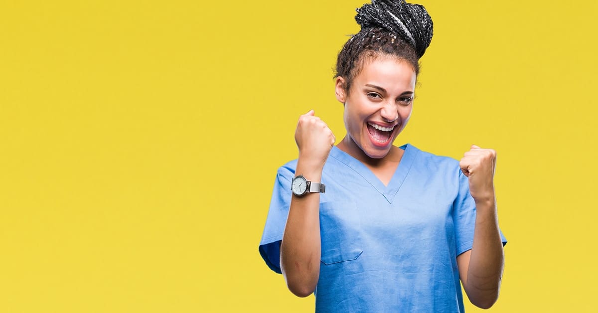 young-female-nurse-pumping-fists-yellow-background