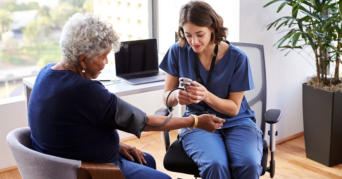 young-female-nurse-taking-blood-pressure-older-patient