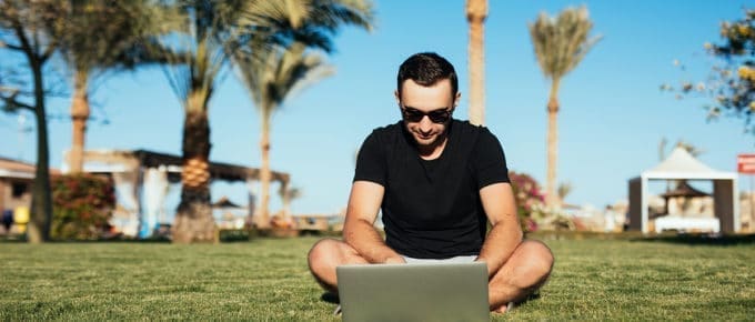man-working-laptop-lawn-palm-trees
