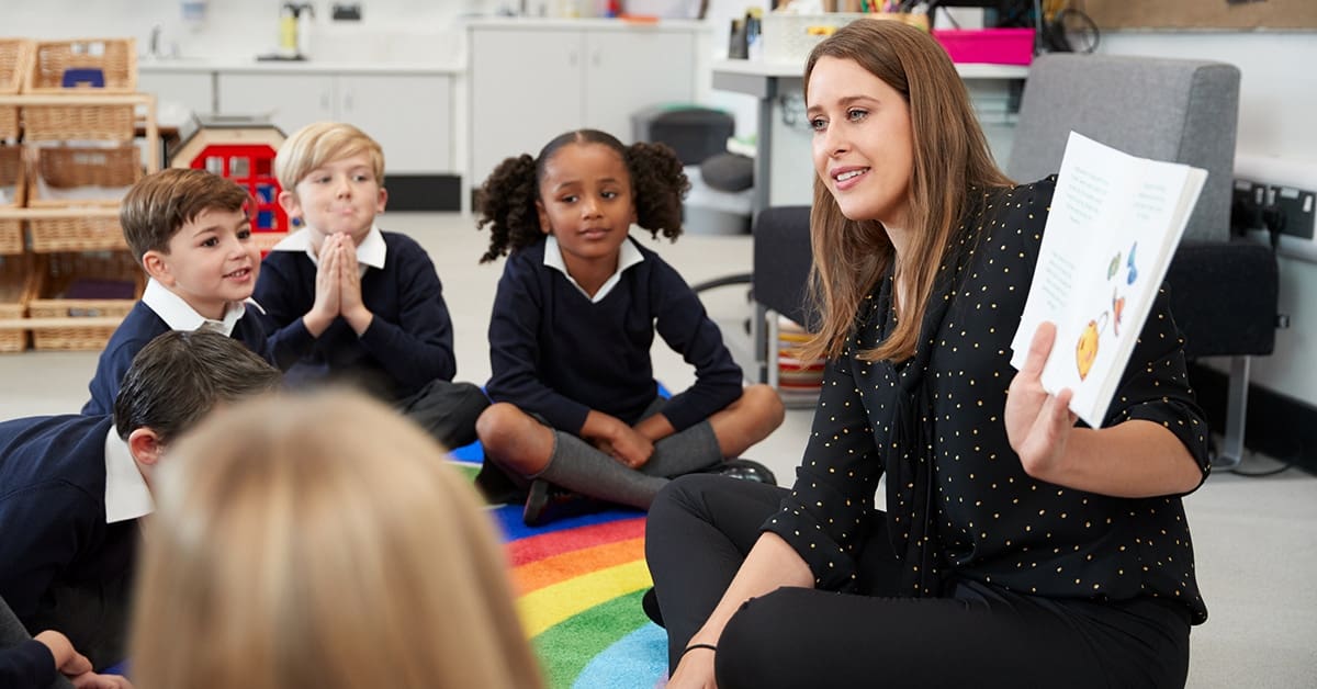 young-woman-teacher-reading-book-primary-students