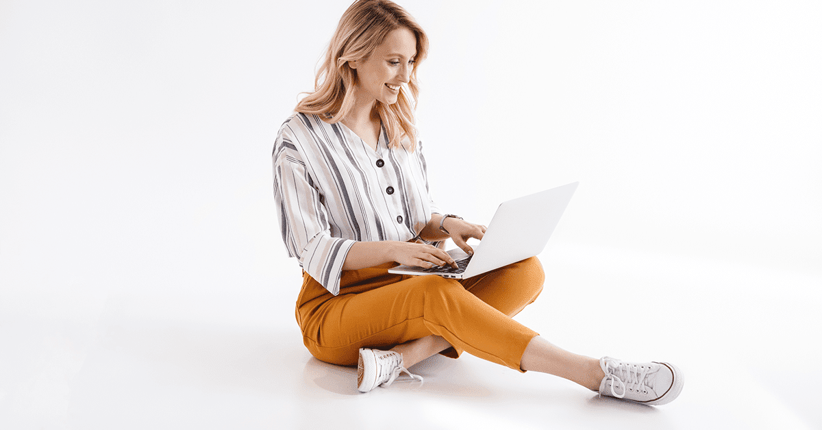 woman-smiling-laptop-sitting-white-studio-background