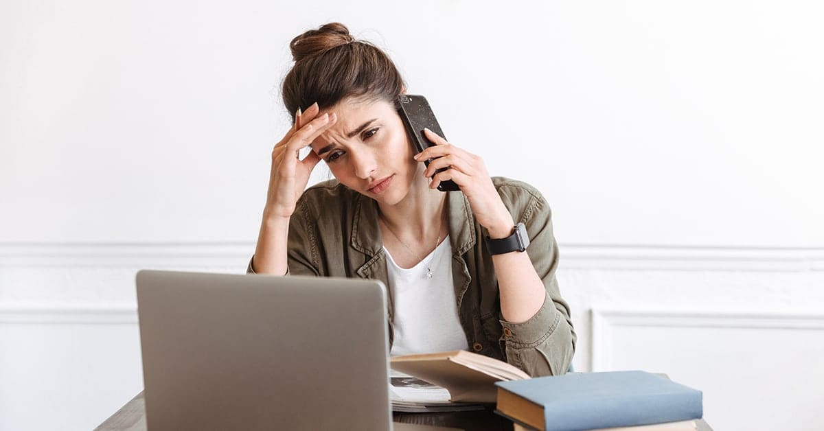 stressed-young-woman-calling-mobile-phone-laptop