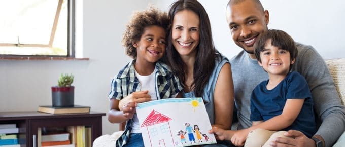 family-parents-two-children-smiling-showing-child's-drawing